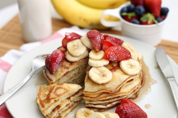 Perfect Buttermilk Pancakes with maple syrup, fresh slices of banana, cut strawberry hearts and icing sugar. Served with soy milk and extra fruit.